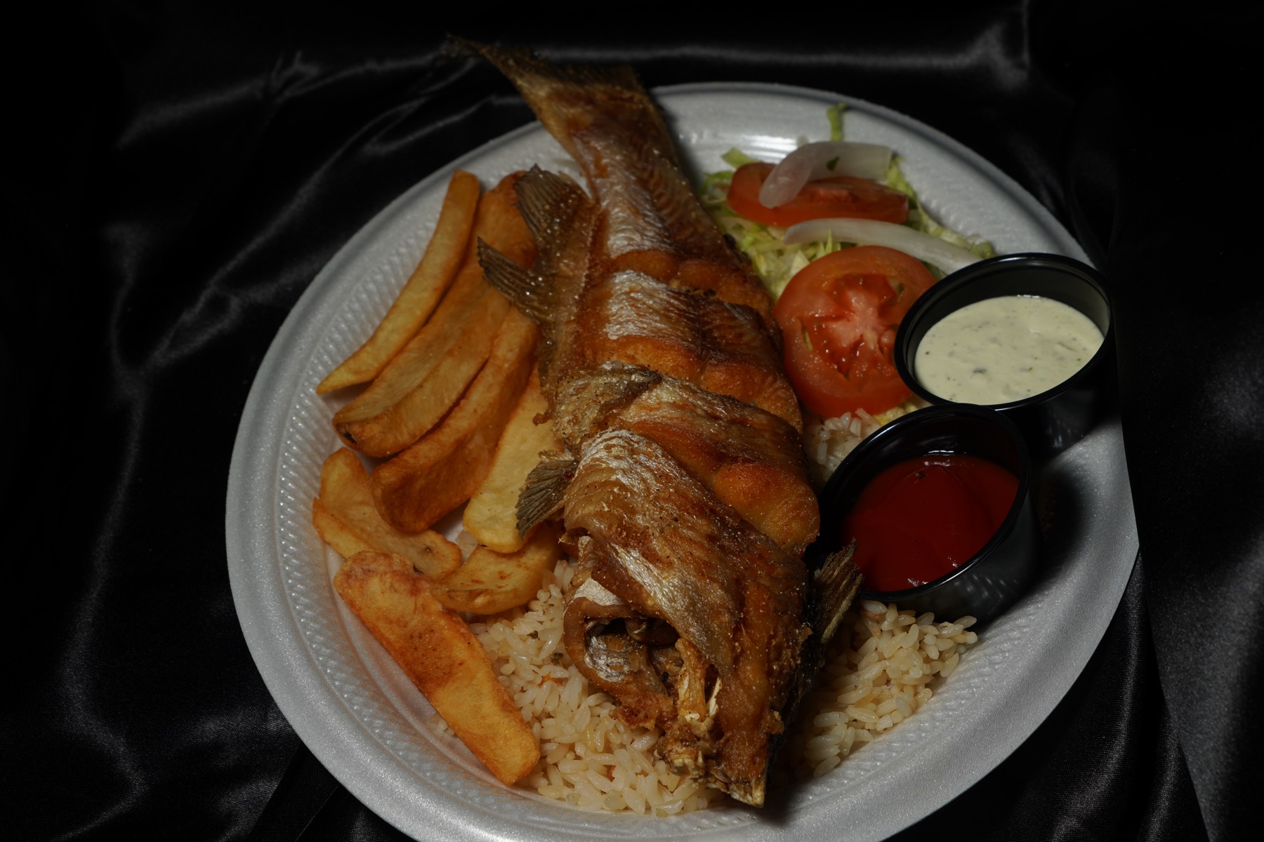 Whole fried fish with rice, fries, and salad